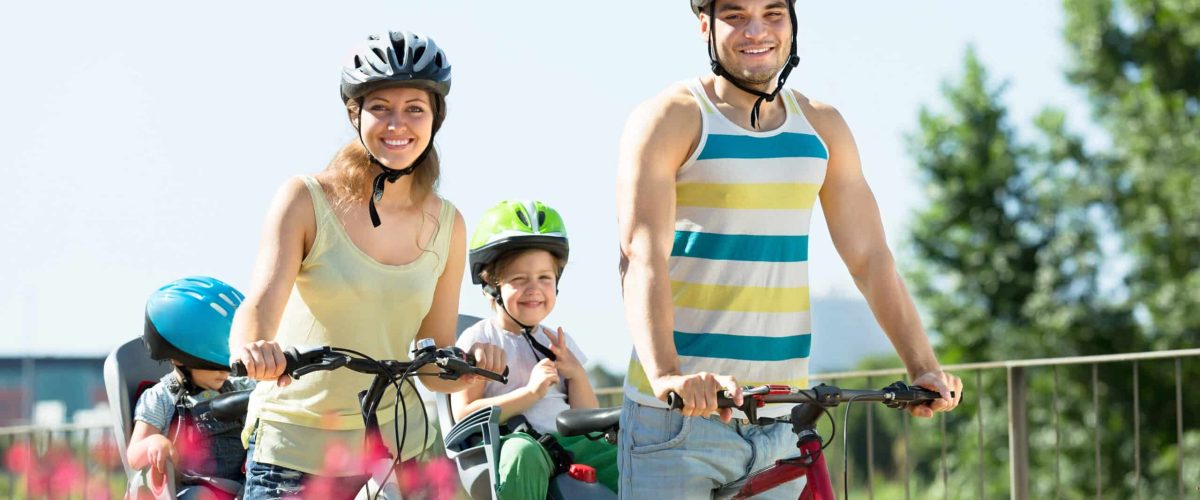 Happy family of four traveling on a bicycle in summer